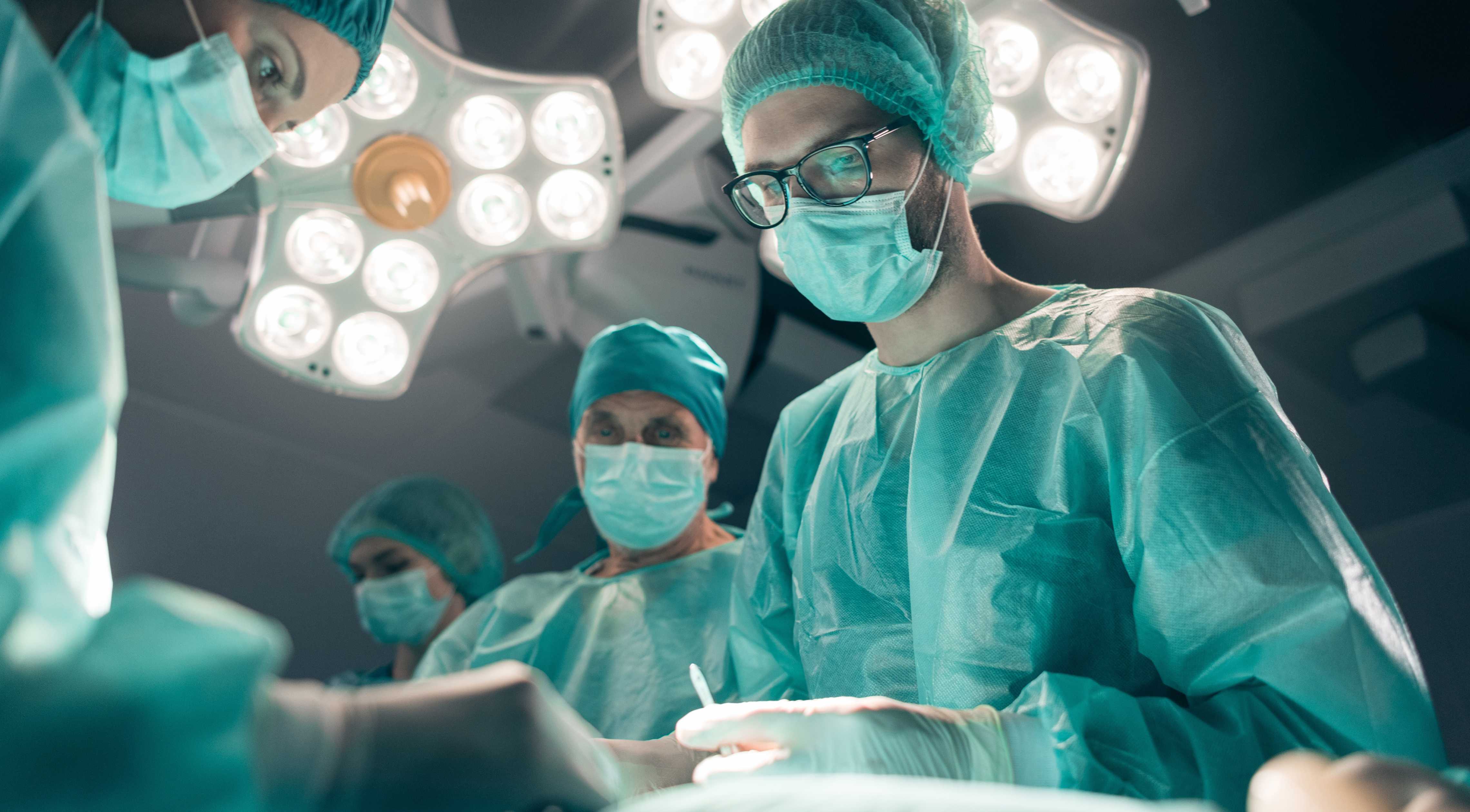 Forside af UX-design-casestudie, der viser kirurger på operationsstuen med lys over hovedet.
